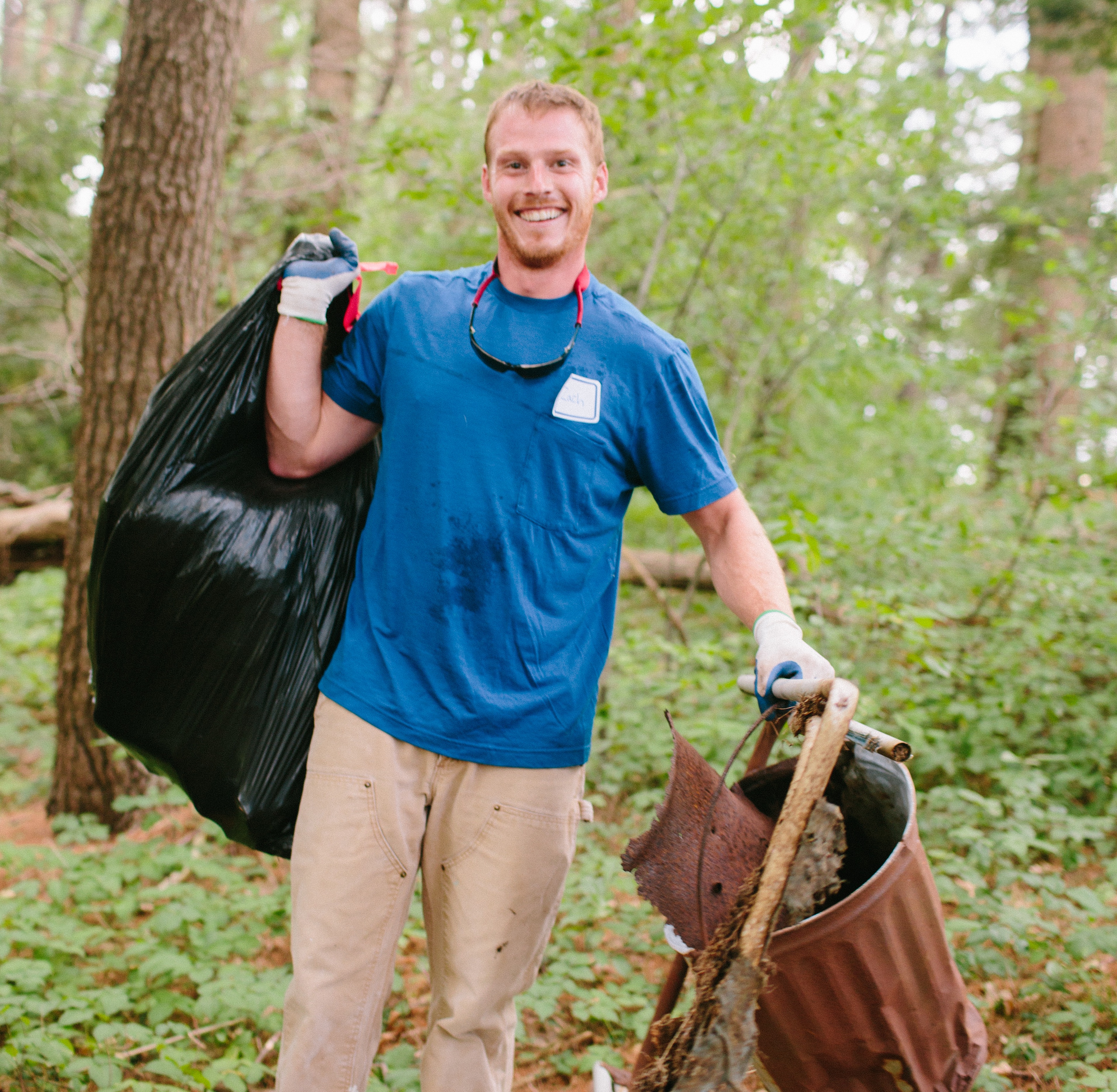 young man picking up trash in woods