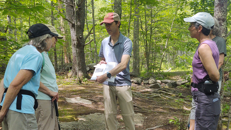 person showing book to volunteers on trail