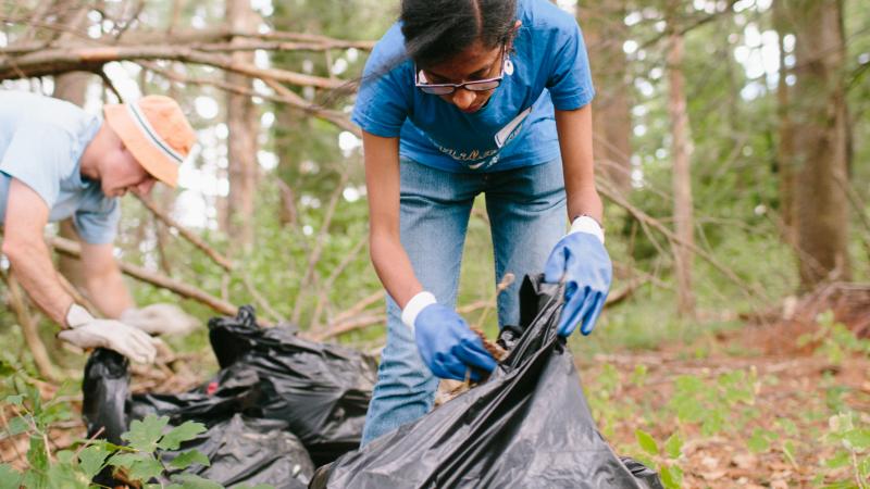 Volunteers cleaning up trash with bags in forest