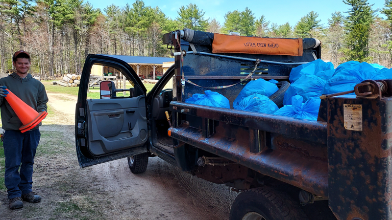 smiling person next to truck full of trash