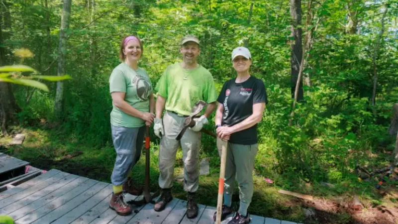 three volunteers standing on bog bridge