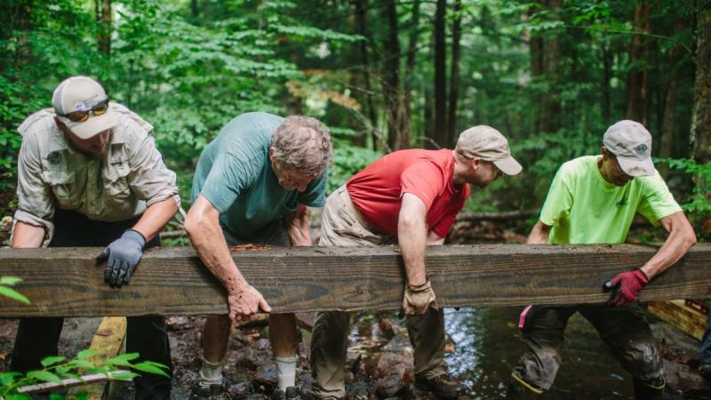 Volunteers helping carry large wooden beam