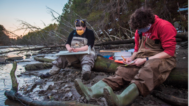 people sitting along river collecting data