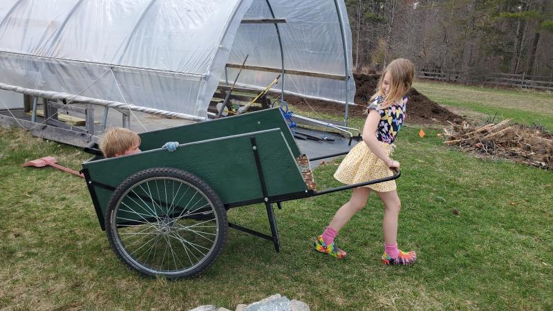 child pulling a cart in a garden
