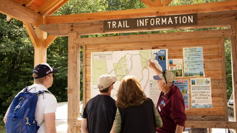 person pointing to trailhead kiosk