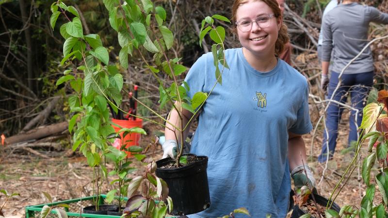 person smiling holding plant