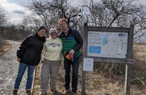 three volunteers smiling at trail kiosk