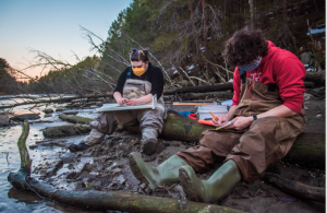 people sitting along river collecting data