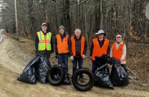 five people standing with bags of trash