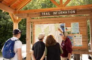 person pointing to trailhead kiosk