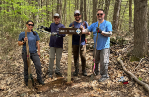 Volunteers standing on trail at sign