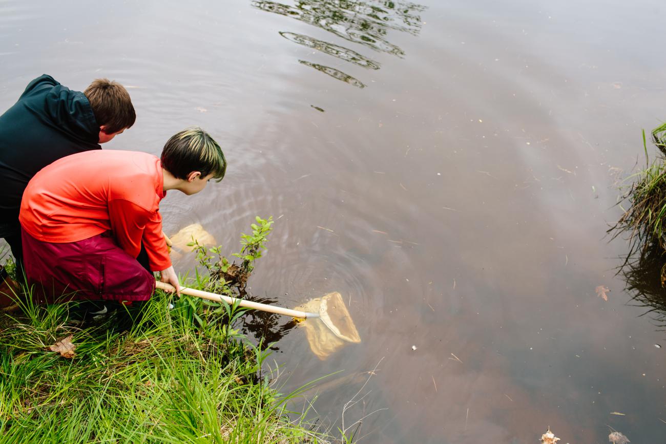 Kids volunteering outdoors with nets at river