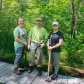 three volunteers standing on bog bridge