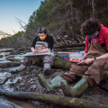 people sitting along river collecting data