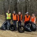 five people standing with bags of trash