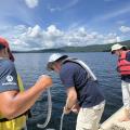 people standing on boat collecting water samples