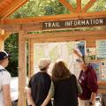 person pointing to trailhead kiosk