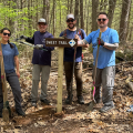Volunteers standing on trail at sign