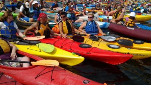 Canoes and kayaks gather together in a floating raft at Raft-a-Palooza
